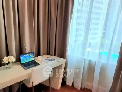 Elegant study area with a desk, laptop, and city view through sheer curtains.