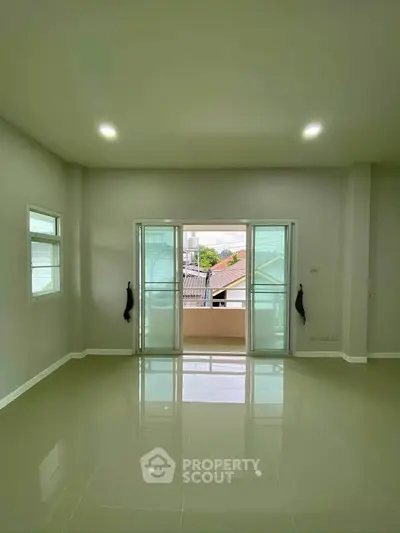 Spacious empty room with glossy tiled floor and balcony view.