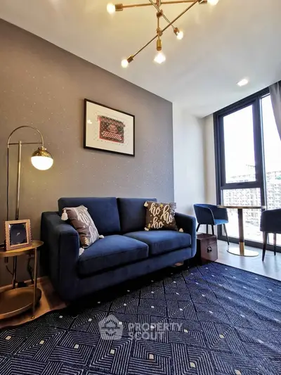 Modern living room with stylish blue sofa, chic decor, and large window offering city views.