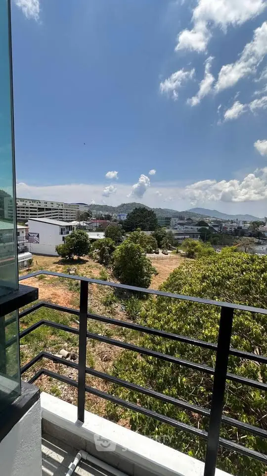 Stunning balcony view with lush greenery and cityscape under a clear blue sky.