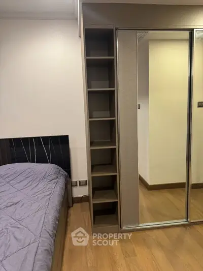 Modern bedroom with built-in shelving and mirrored closet doors