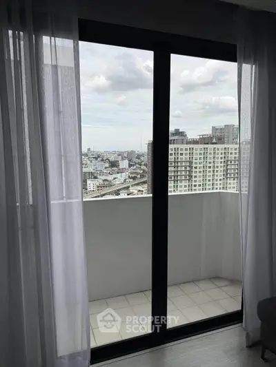 Modern apartment with balcony offering stunning city views through glass doors.