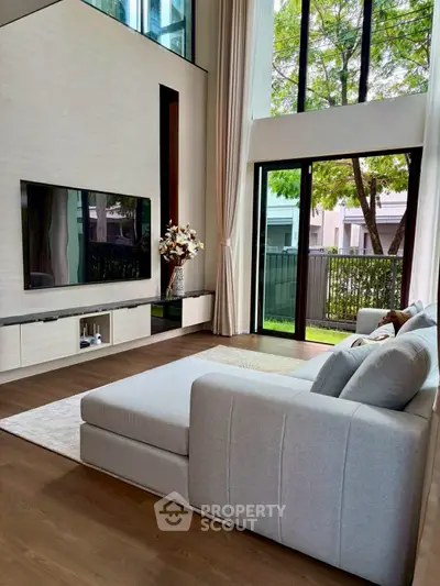 Luxurious living room with high ceilings, large windows, and modern decor.