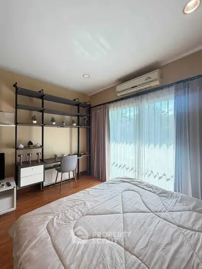 Cozy bedroom with study area and large window offering natural light