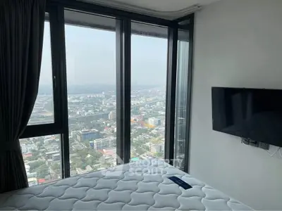 Modern bedroom with panoramic city view and wall-mounted TV