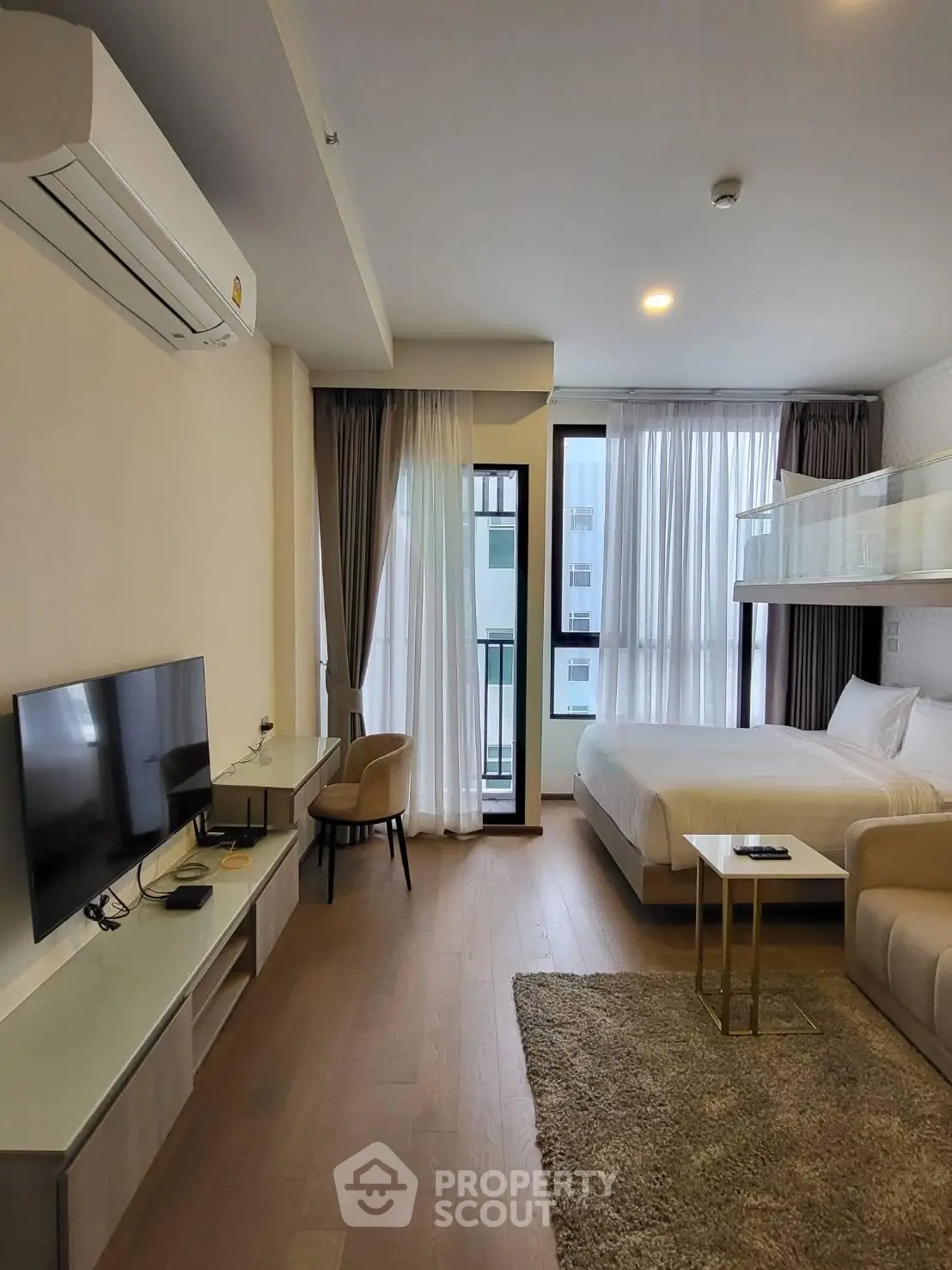 Modern studio apartment with cozy living area and large windows for natural light.