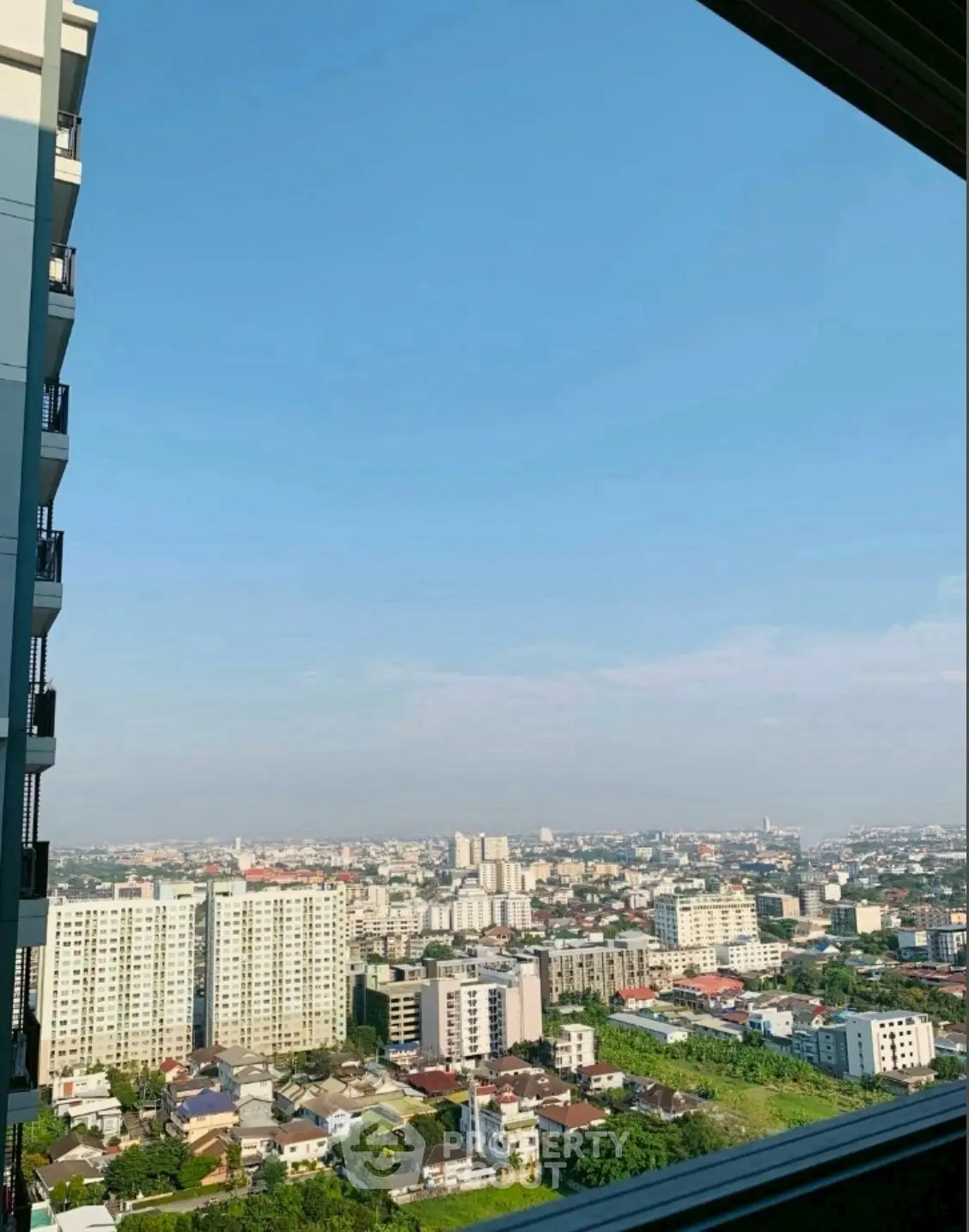 Stunning cityscape view from high-rise balcony showcasing urban skyline and greenery.