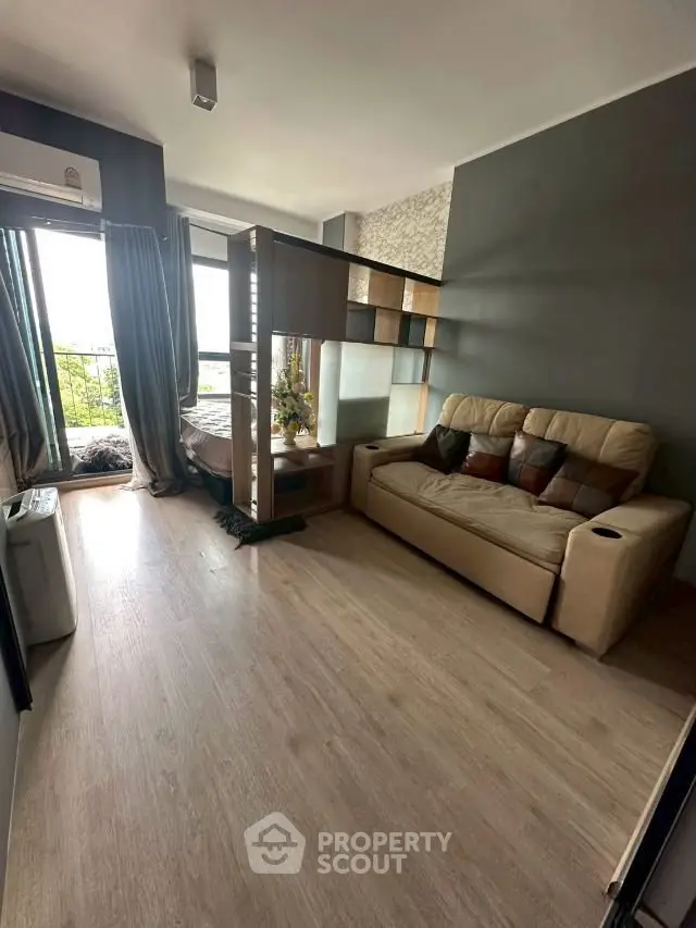 Modern studio apartment with stylish partition and cozy living area, featuring a comfortable sofa and natural light.