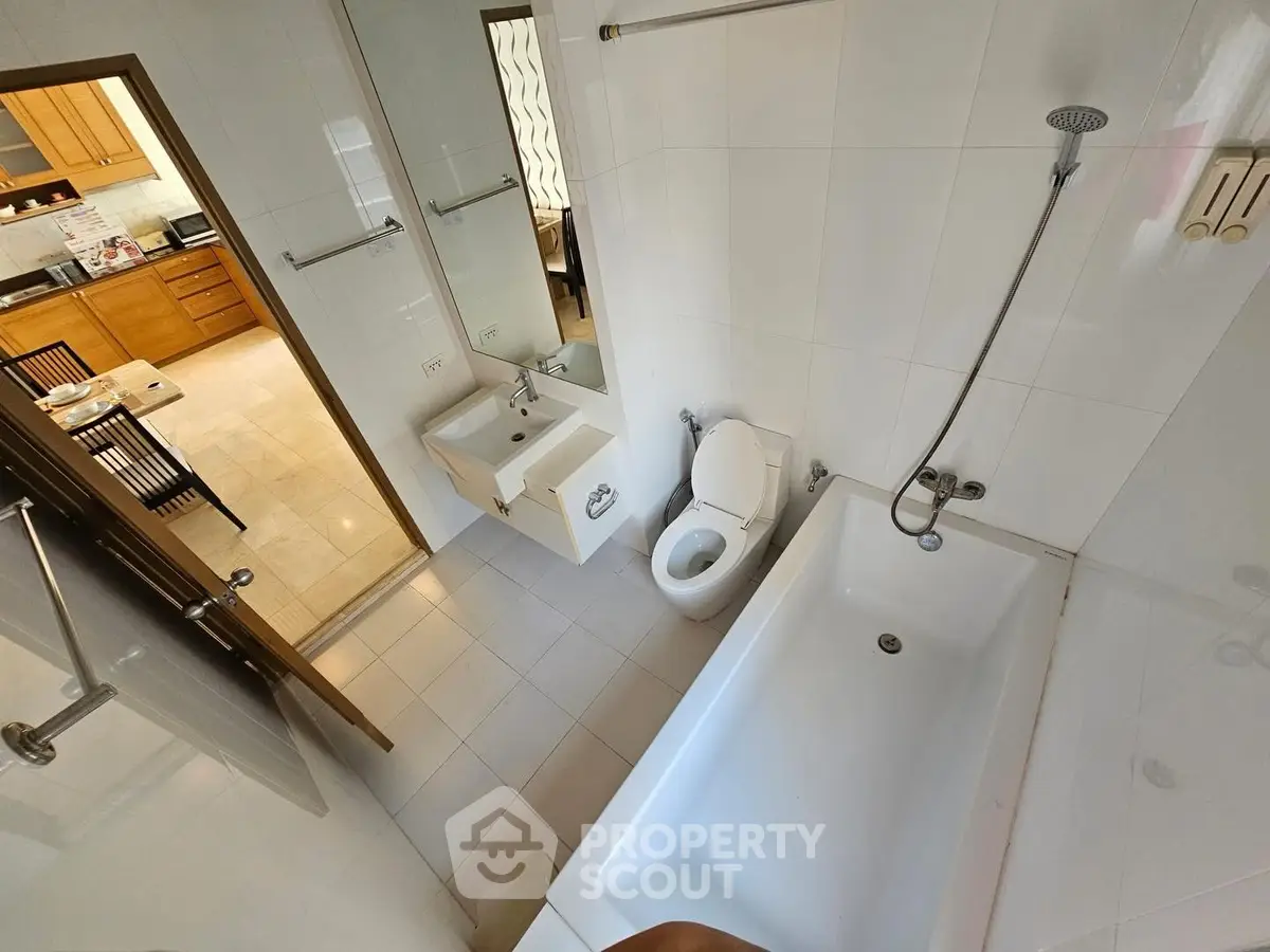Modern bathroom with bathtub and view into stylish kitchen