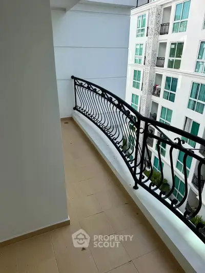 Spacious balcony with elegant railing and city view in modern apartment building.