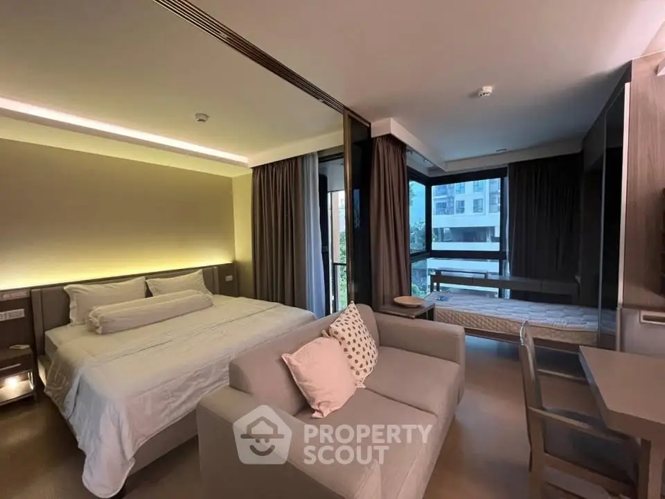 Modern bedroom with cozy seating area and large windows offering natural light