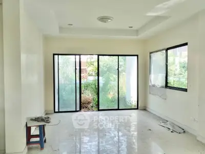 Spacious living room with large windows and garden view, perfect for natural light lovers.