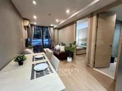 Modern open-plan living room with dining area and view of cozy bedroom, featuring stylish decor and natural lighting.