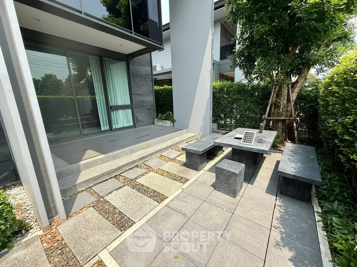 Modern outdoor patio with stone seating and lush greenery