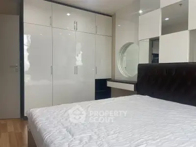Modern bedroom with sleek white wardrobes and stylish bed in a contemporary apartment.