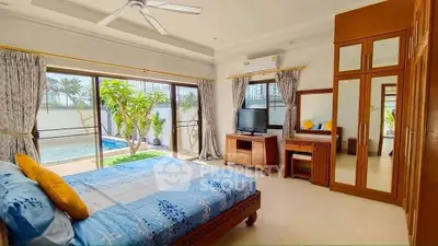Spacious bedroom with pool view, elegant wooden furniture, and large windows for natural light.
