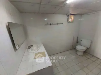 Spacious bathroom with tiled walls and floor, featuring a sink and toilet.