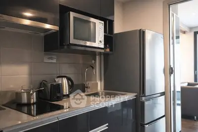 Modern kitchen with sleek appliances and open layout, featuring stainless steel fridge and microwave.