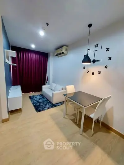 Modern living room with stylish decor and wall clock, featuring cozy seating and dining area.