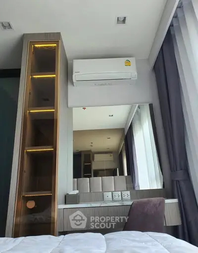 Modern bedroom with sleek design, featuring built-in shelving and air conditioning.