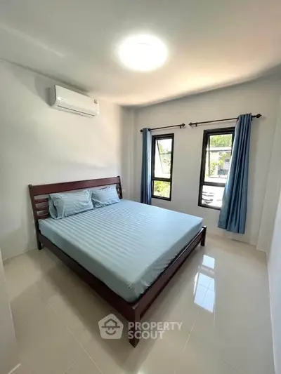 Bright and airy bedroom with large windows and modern furnishings in a stylish home.