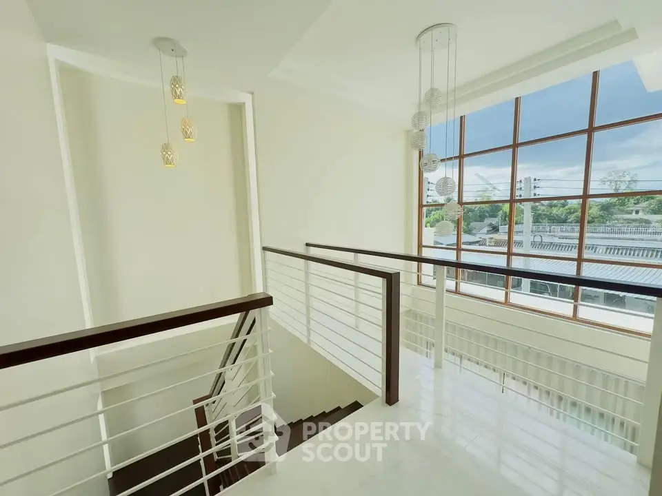 Elegant staircase with large windows offering a stunning view, modern lighting, and sleek railing design.