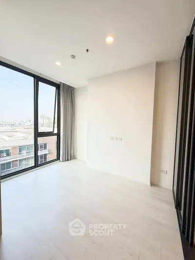 Spacious modern room with large windows and city view, perfect for urban living.