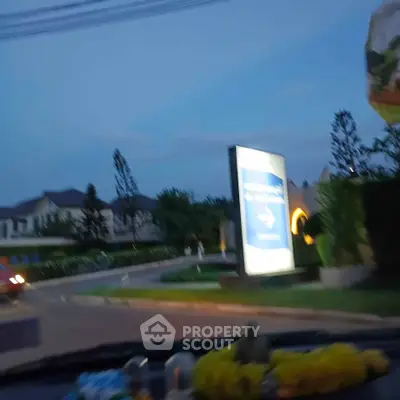 Charming suburban neighborhood entrance with lush greenery and elegant homes at dusk.