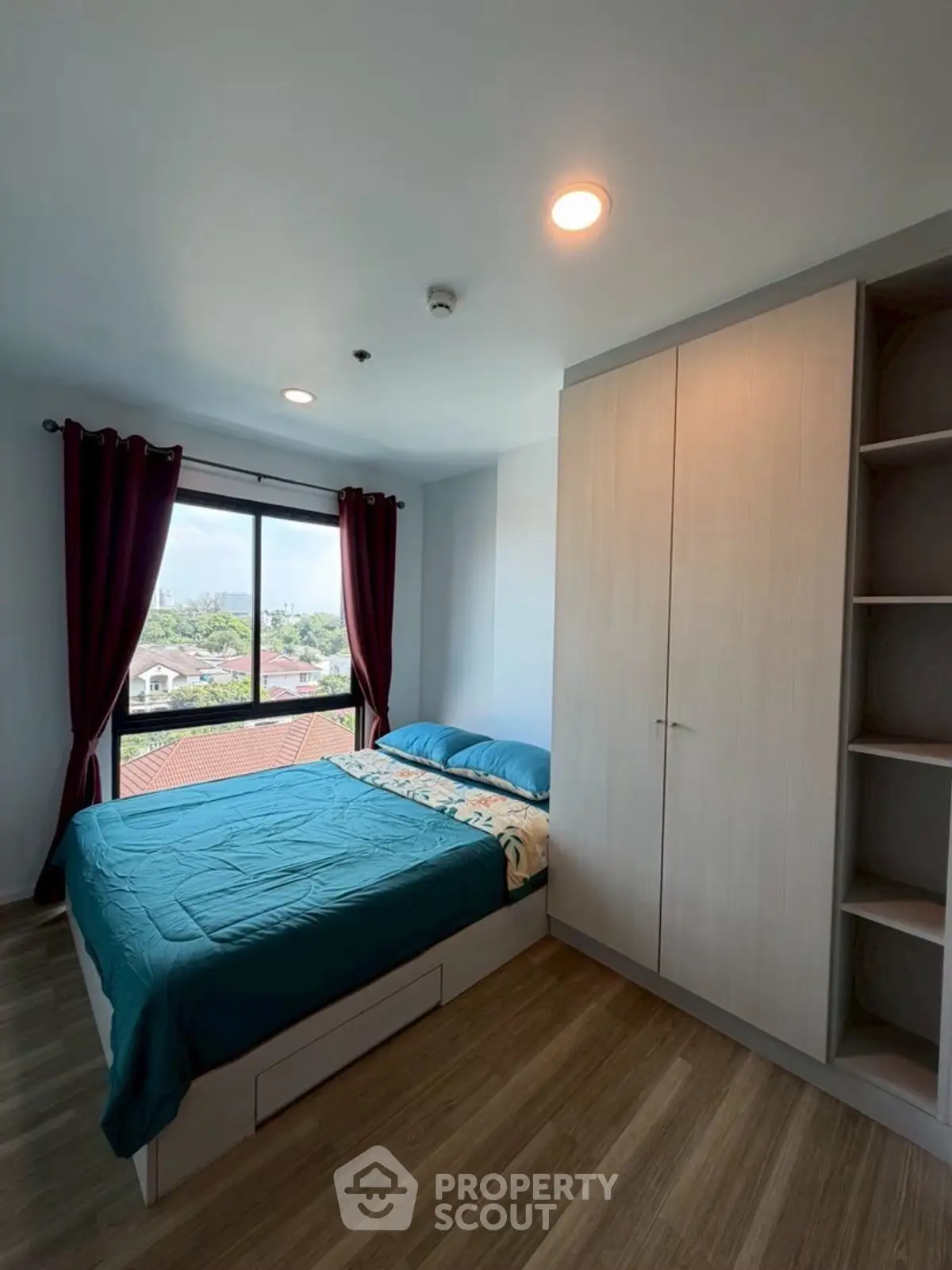 Cozy bedroom with large window offering scenic views, featuring modern furnishings and ample storage space.