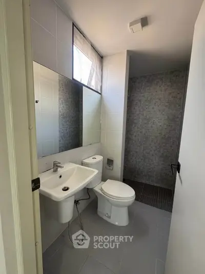 Modern bathroom with sleek fixtures and tiled shower area in a contemporary home.