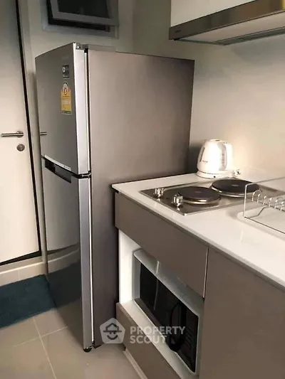 Modern kitchen with sleek appliances and compact design, featuring a fridge, stove, and microwave.