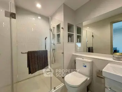 Modern bathroom with glass shower enclosure and sleek fixtures in a contemporary home.