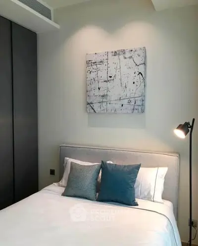 Modern bedroom with stylish decor and cozy lighting, featuring a comfortable bed and abstract wall art.
