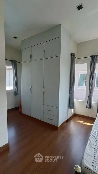 Spacious bedroom with built-in wardrobe and large windows for natural light