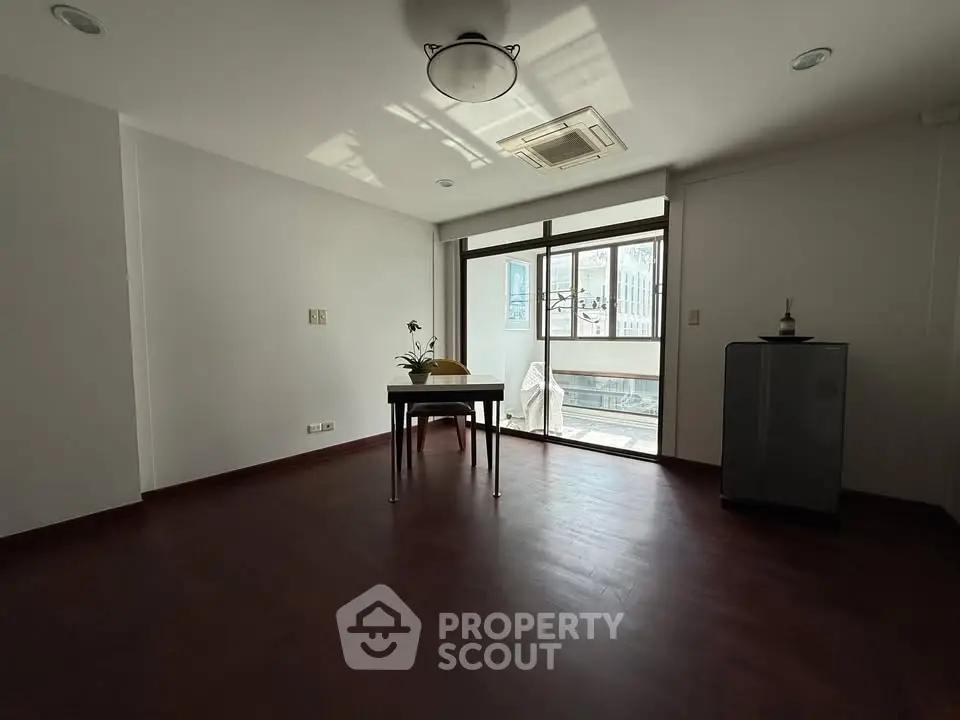 Spacious room with large window and minimalist decor, perfect for versatile use.