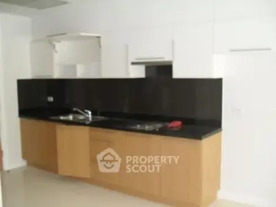 Modern kitchen with sleek black countertops and wooden cabinets in a contemporary apartment.