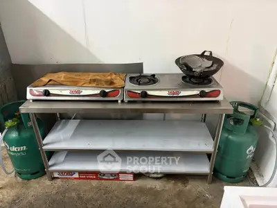 Compact kitchen setup with gas stoves and storage shelves, ideal for efficient cooking space.