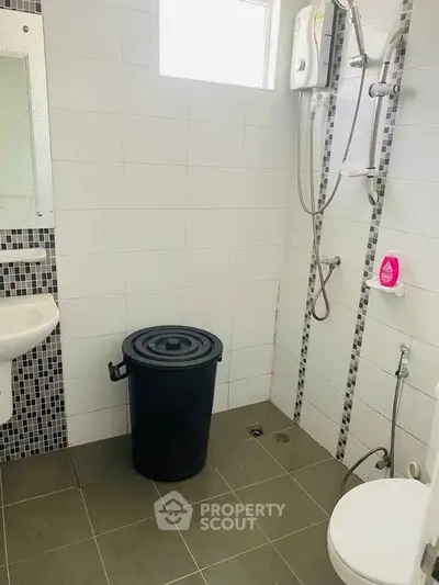 Modern bathroom with shower and tiled walls, featuring a sleek design and practical layout.