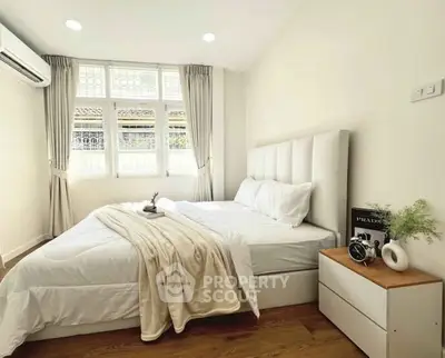 Bright and cozy bedroom with modern decor and large window, perfect for relaxation.