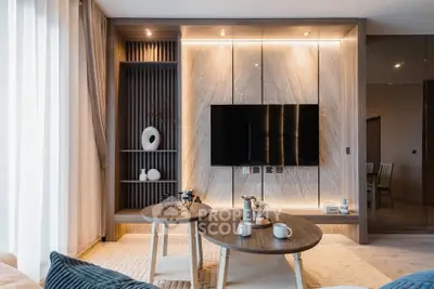 Modern living room with stylish decor and wall-mounted TV, featuring elegant lighting and contemporary furniture.