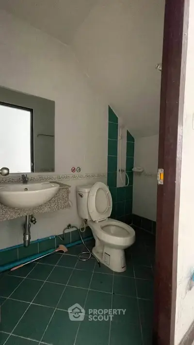 Compact bathroom with green tiles and modern fixtures in cozy real estate property.
