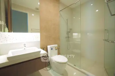 Modern bathroom with glass shower and sleek fixtures in contemporary apartment.