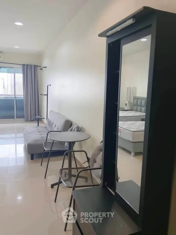 Modern studio apartment with sleek furniture and natural light, featuring a cozy living area and a comfortable bed.