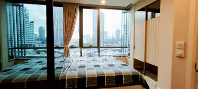 Modern bedroom with city view and large windows in high-rise apartment