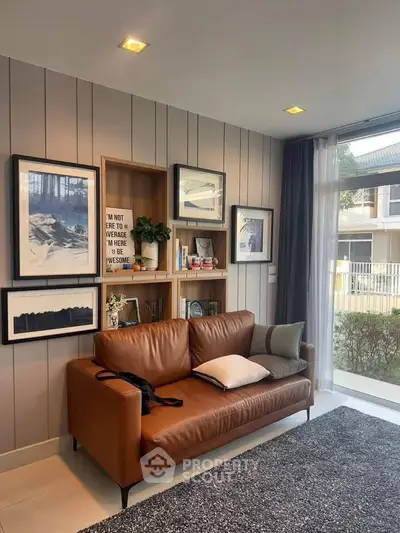 Stylish living room with leather sofa and modern decor, large window view.