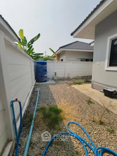 Charming residential backyard with gravel path and modern fencing, perfect for outdoor activities.