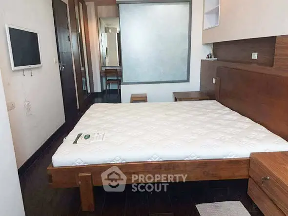 Modern bedroom with wooden furniture and wall-mounted TV, showcasing a minimalist design.