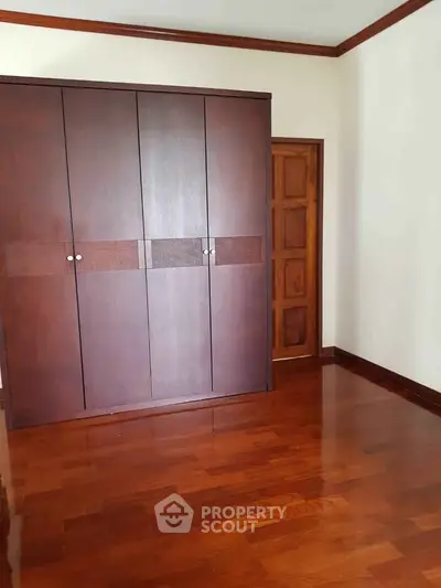 Spacious bedroom with elegant wooden flooring and built-in wardrobe, perfect for modern living.