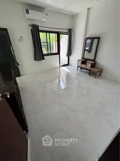 Spacious unfurnished bedroom with large window and air conditioning