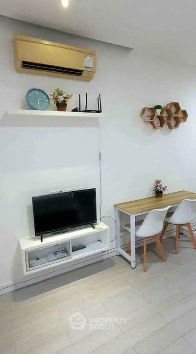Modern living room with minimalist decor, featuring a wall-mounted TV, air conditioning, and stylish furniture.
